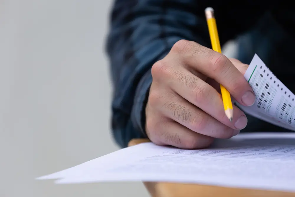 Candidat en salle d'examen remplissant un questionnaire QCM lors des épreuves de sélection pour un emploi fédéral.