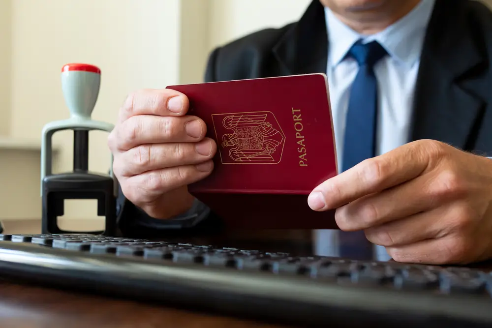 Douanier à son bureau effectuant un contrôle de passeport devant son clavier d'ordinateur.