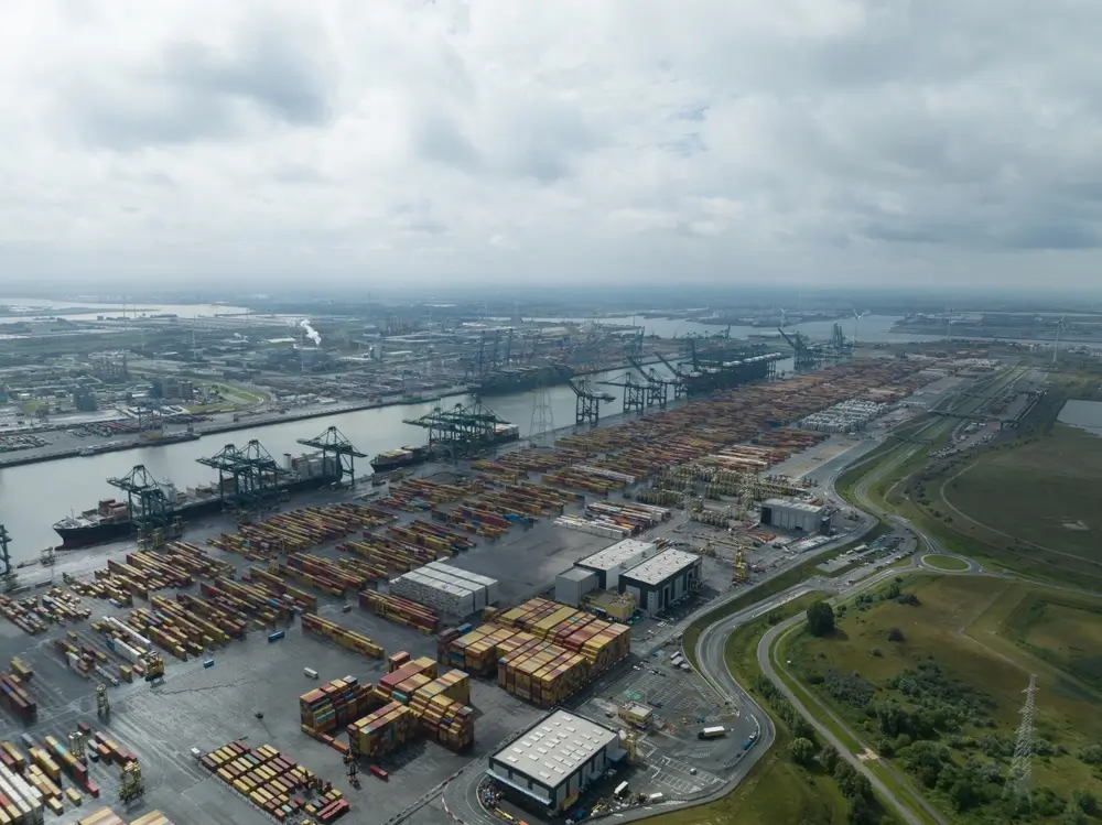 Vue aérienne d'un terminal du port d'Anvers avec des navires de marchandises et des milliers de conteneurs alignés.