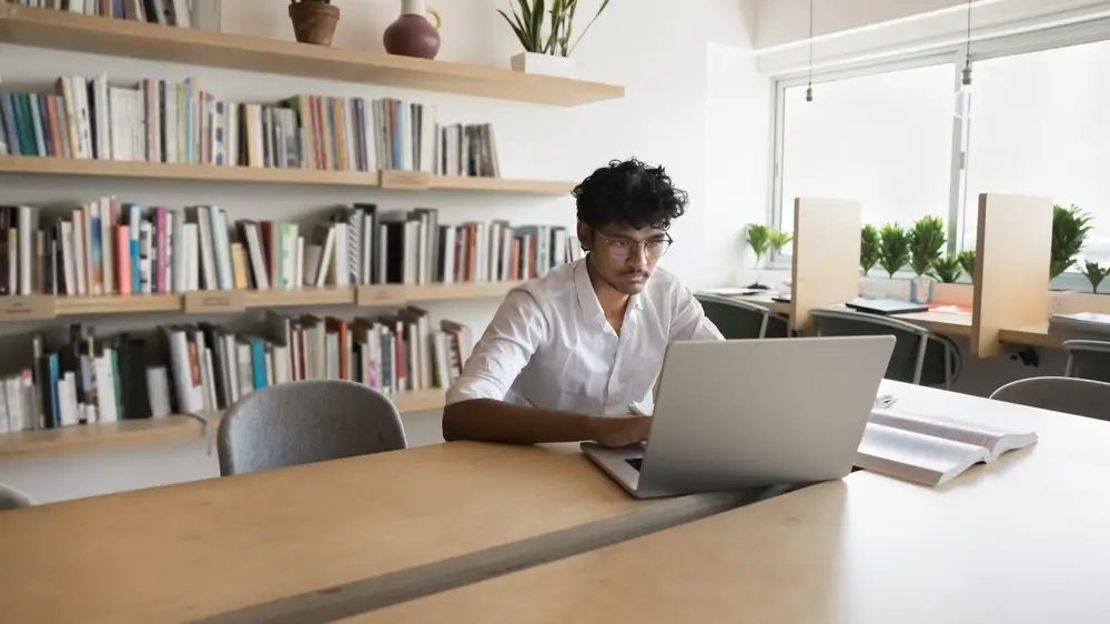 Un candidat concentré passe un test informatisé d'évaluation pour un emploi sur son ordinateur portable au bureau.