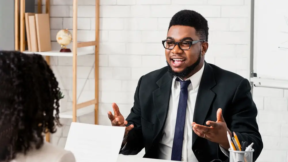 Recruteur souriant échangeant avec une candidate lors d'un salon de l'emploi pour des opportunités de carrière.