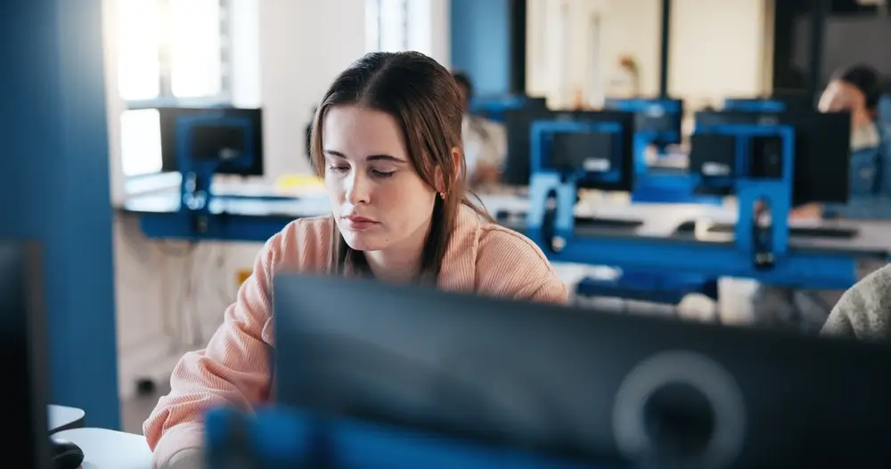 Une candidate concentrée passant un test informatisé de sélection sur ordinateur dans une salle d’examen.