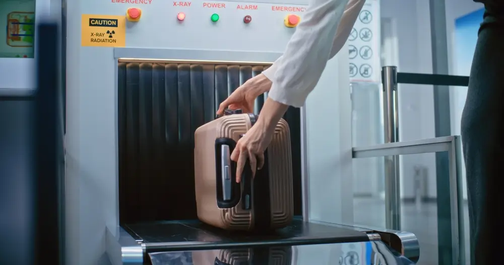 Valise déposée sur le tapis d'un scanner à rayons X pour un contrôle douanier de sécurité.