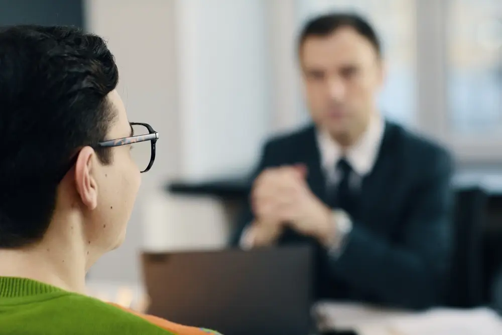 Candidat de profil échangeant avec un recruteur lors d'un entretien oral d'évaluation des compétences comportementales.