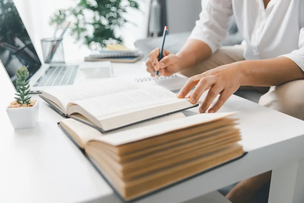 Livres de préparation aux concours ouverts pour une session d'étude avec prise de notes manuscrites sur un bureau.